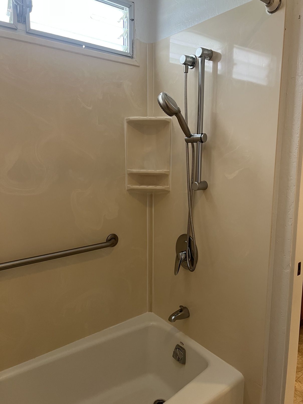 A white bathtub with a shower head and hand held shower.